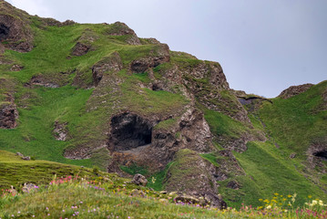View of small mountain cave in green mountains in summer