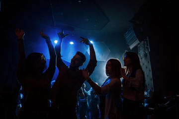 Fototapeta premium Happy youth. Group of people that enjoying dancing in the nightclub with beautiful lightings