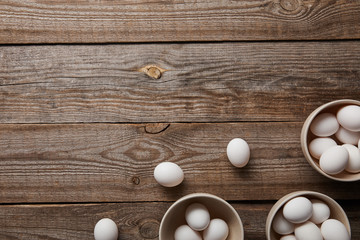 top view of chicken eggs in bowls on wooden table