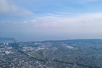 Aerial view of a large number of small houses with colored roofs on the outskirts of a big city on an summer sunny day with the road and cars near river and sky