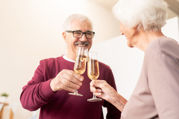 Mature husband and wife clinking with flutes of champagne