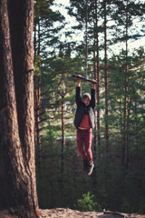 Teen boy at bungee in autumn forest in beauty sunny day