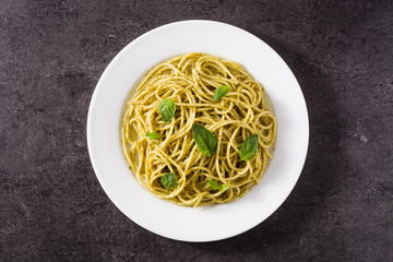 Spaghetti pasta with pesto sauce on black background. Top view