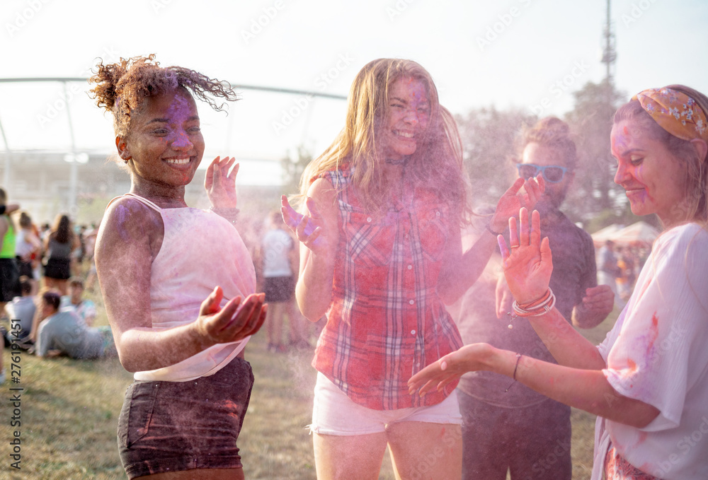 Wall mural Multiethnic group of friends throwing colorful powder at holi festival