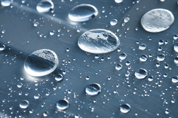Close-up of raindrops of different sizes on the surface covered with cling film. Moisture weather and humidity concept