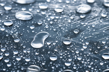 Close-up of raindrops of different sizes on the surface covered with cling film. Moisture weather and humidity concept