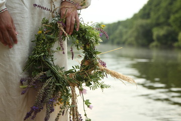 The girl in Slavic clothes with a wreath on the background of the river