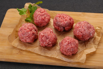 Raw meatball over wooden background