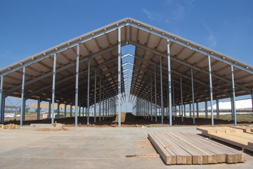 Construction of agricultural facilities. Wooden beams for the construction of the roof against the background of a village hangar under construction © Vasiliy Ulyanov