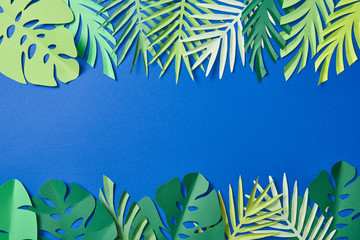 top view of green exotic leaves on blue background with copy space