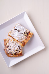 Two pieces of homemade cookies apricot jam powdered sugar in white square plate