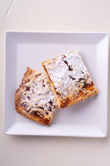 Two pieces of homemade cookies apricot jam powdered sugar in white square plate
