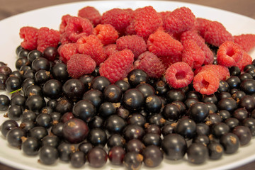 blueberries and raspberries in a plate on a wooden table