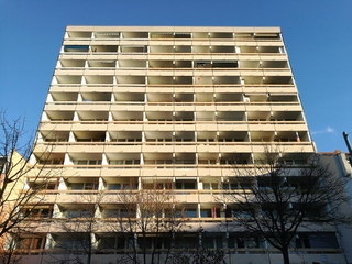 Modernes Hochhaus mit Mietwohnungen und Apartments am Morgen vor blauem Himmel im Sonnenschein in...