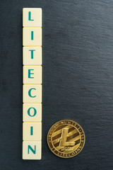 Physical Litecoin gold coin with text made out of letter tiles. Cryptocurrency. Vertical orientation. Copy space on the right.