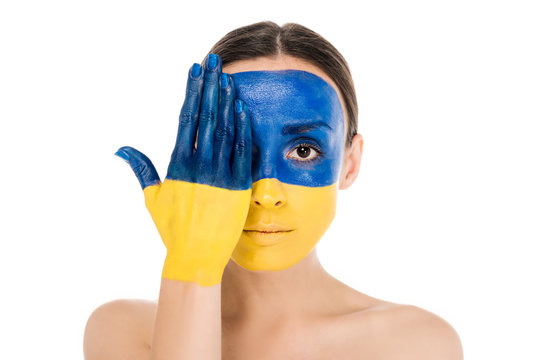 serious naked young woman with painted Ukrainian flag on skin isolated on white