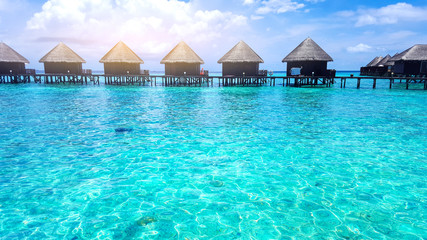 Fototapeta na wymiar Wooden bungalow water villa in tropical style over the crystal blue sea water at Maldives island on a sunny day for summer holiday vacations concept.