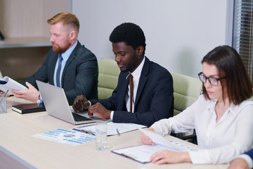 Young intercultural colleagues in formalwear working individually