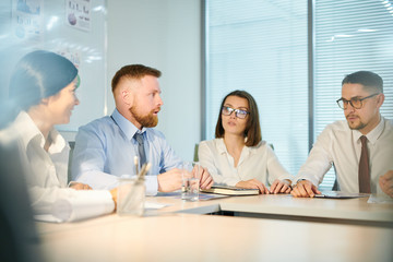 Four young colleagues preparing for conference in boardroom