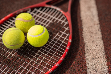 Three yellow tennis spheres lying on racket by white line