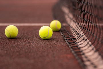Three yellow tennis balls on court or playground and net