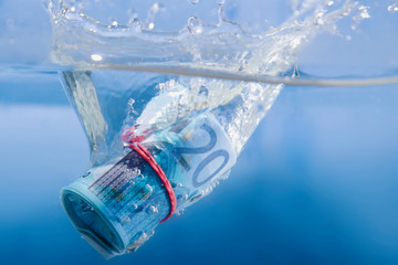 Money concept. Euro banknote sinking in water as a symbol of global economic crisis