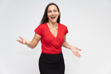 Portrait to the waist of a young pretty brunette woman of 30 years old in a bright red sweater with beautiful dark hair. Standing on a white background, talking, showing hands, with emotions