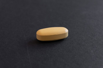 Obraz na płótnie Canvas yellol pill, tablet isolated on dark / grey background