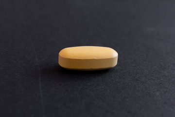 Obraz na płótnie Canvas yellol pill, tablet isolated on dark / grey background