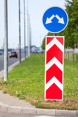 Road sign with two directions for driving, asphalt roadside at summer
