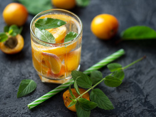 Summer apricot drink cocktail with pieces of fruit and mint