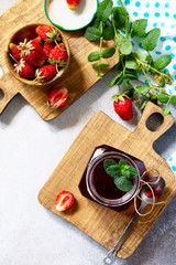 Homemade preservation. Fresh strawberry berries and strawberry berry syrup on a light stone table. Top view flat lay background.