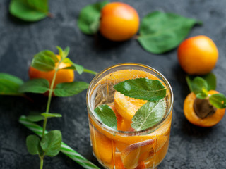 Summer apricot drink cocktail with pieces of fruit and mint