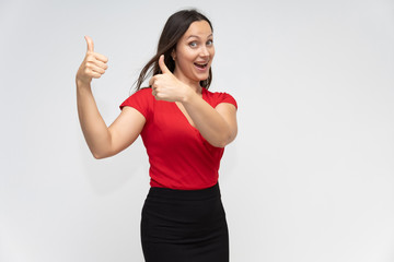 Fototapeta premium Portrait to the waist of a young pretty brunette woman of 30 years old in a bright red sweater with beautiful dark hair. Standing on a white background, talking, showing hands, with emotions