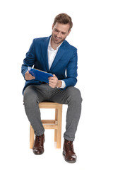 Joyful casual guy laughing and reading from a clipboard