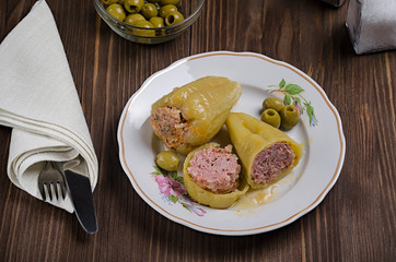 stewed green pepper stuffed with meat on a wooden background, with olives and salt in a flask, top view