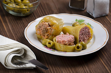 stewed green pepper stuffed with meat on a wooden background, with olives and salt in a flask, 45 view