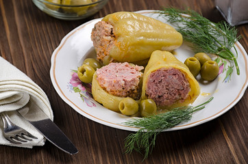 stewed green pepper stuffed with meat on a wooden background, with olives and salt in a flask, 45 view