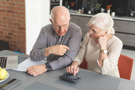 Senior Couple Paying Bills Together On Laptop