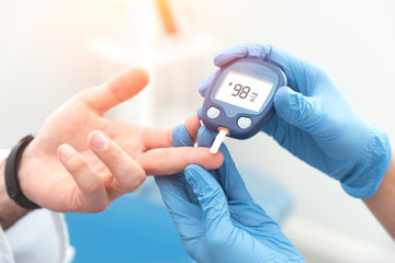 Doctor checking blood sugar level with glucometer - obrazy, fototapety, plakaty