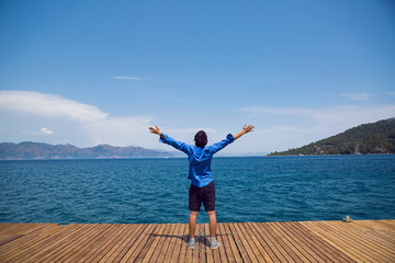 guy stands by the sea on the pier in a blue shirt
