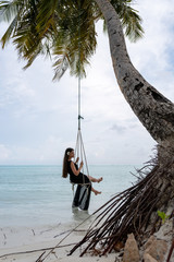 A young girl riding on a swing. Swing suspended on the palpe above the water