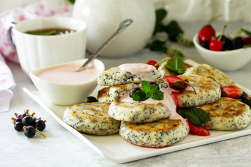 Summer breakfast background. Homemade cottage cheese pancakes with poppy seeds, served sour cream sauce with strawberries.