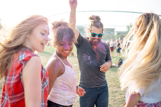 Cheerful friends with color paint on bodies dancing at holi festival