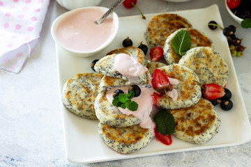 Summer breakfast background. Homemade cottage cheese pancakes with poppy seeds, served sour cream sauce with strawberries. Free space for your text.