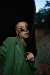 Beautiful girl on the hill in a green jacket and sunglasses. Fashion portrait