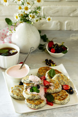Summer breakfast background. Homemade cottage cheese pancakes with poppy seeds, served sour cream sauce with strawberries.
