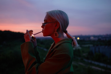 Beautiful girl on the hill in a green jacket and sunglasses. Fashion portrait