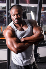 The athlete listens to music on headphones from his smartphone in the gym