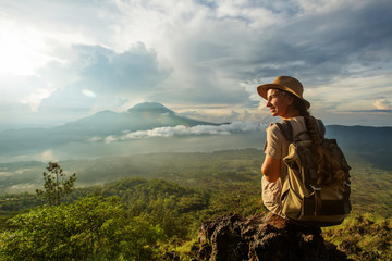 Woman enjoying sunrise from a top of mountain Batur, Bali, Indonesia.